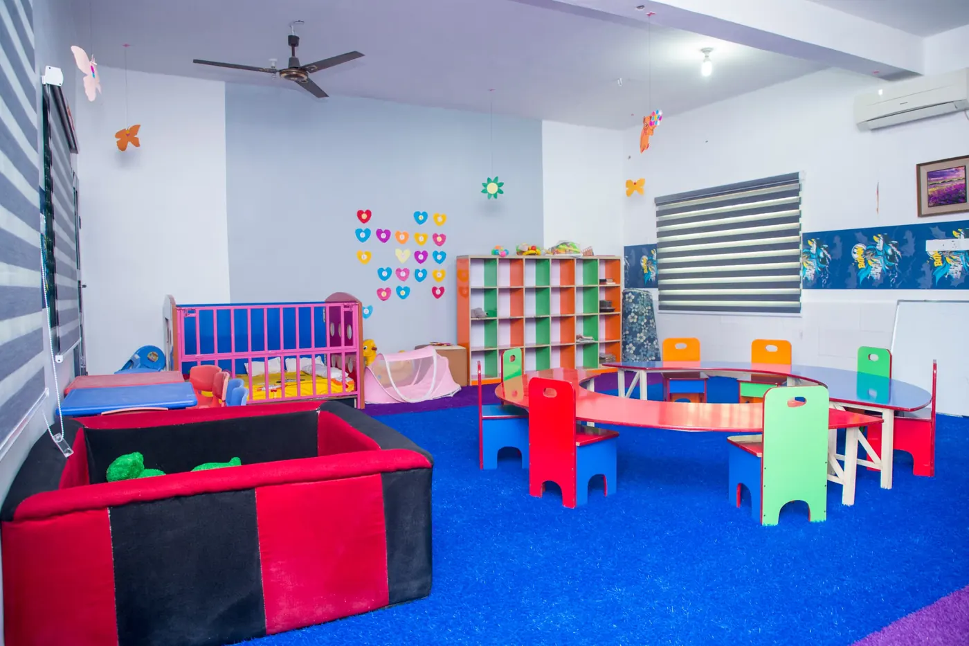 The crèche playroom with a soft play pen, cot and small colourful chairs