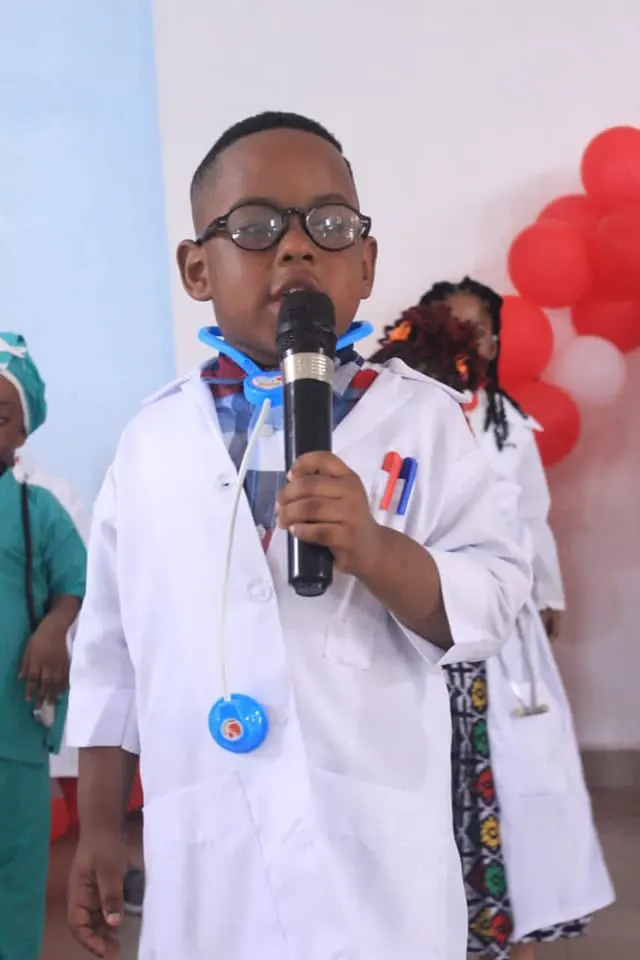 A pupil in a white lab coat giving a presentation with a microphone