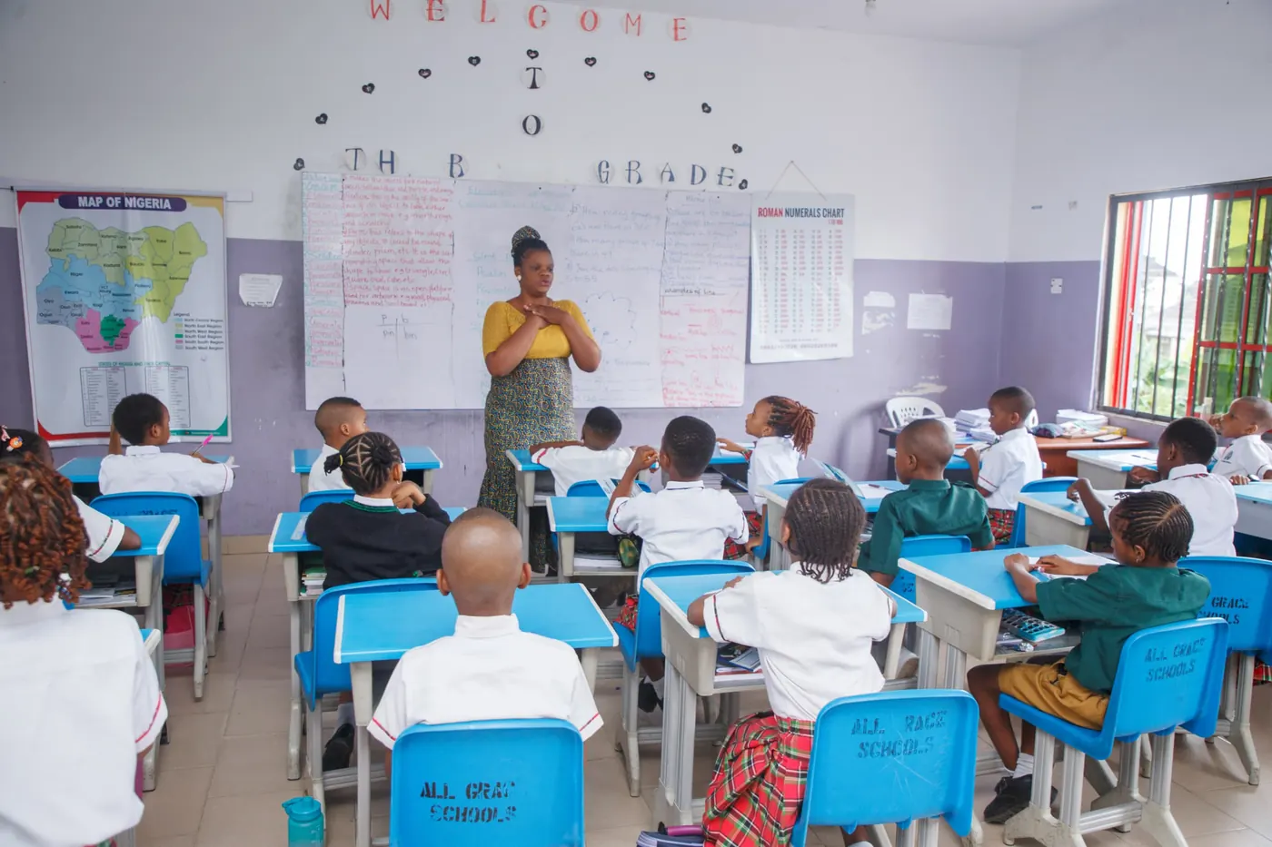 A teacher leads a lesson at the whiteboard while pupils sit at their desks